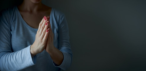 Wall Mural - A woman prays with faith to GOD. Religion care during the pandemic crisis. Hands folded in prayer.