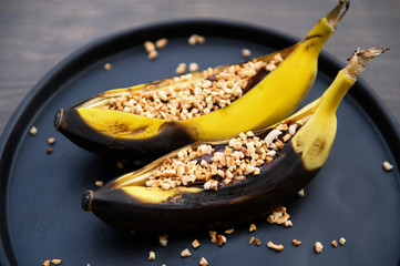 Two ripe bananas grilled with chocolate, sprinkled with almond chips. Top view. Selective focus.