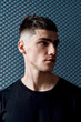 © Svitlana - Time for new haircut. Portrait of a handsome young man in black T-shirt with stylish haircut looking away while posing against dark blue background. Barbershop