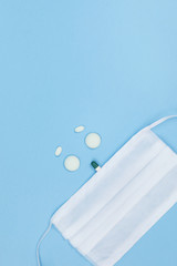 Blue table with round pills in the form of a face, a medicinal mask on it. Top view, copy space. Medicine concept photo. High viewing angle, place for text.