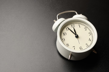 Wall Mural - White vintage alarm clocks show almost midday or midnight isolated on black table background.