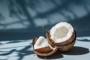 half a coconut and pieces of coconut on a blue background.