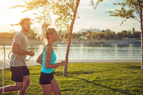 Mata magnetyczna Współczesna kobieta i mężczyzna jogging / ćwiczenia w otoczeniu miejskim w pobliżu rzeki.