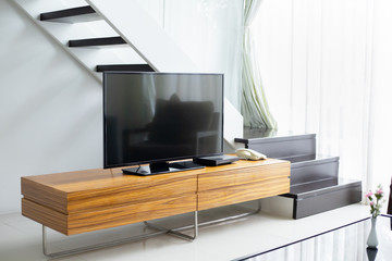 Smart TV wide screen stand on cabinet wooden in the modern living room. Concept of less is more interior design