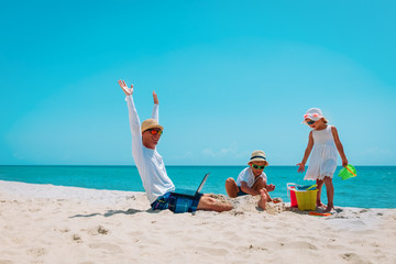 Wall Mural - happy father with laptop trying to work and kids play with sand on beach