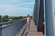 © Smile - Pretty young woman posing on the old rusty transport bridge over the river during sunset.