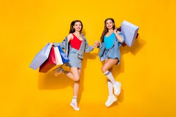 Sticker - Full length body size view of nice attractive pretty glamorous slender cheerful girls carrying buyings jumping shadow friends friendship isolated on bright vivid shine vibrant yellow color background