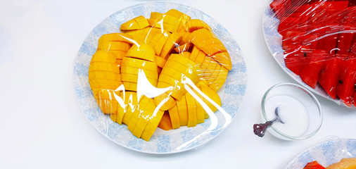 Wall Mural - Fresh Ripe mango sliced and watermelon wrapping plastic in dish or plate with coconut milk bowl isolated on white background with copy space. Diet food and Tropical fruit.