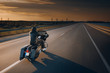 Motorcycle driver riding alone on asphalt motorway. Biker in the motion at the empty road