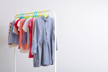 Wall Mural - Children clothes on a rack on a light background. Children's clothing, children's stores.
