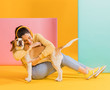 Happy woman hugging a cute dog. Colorful creative yellow studio background.