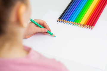 Sticker - Little girl is drawing on white paper using color pencil. Copy space for text. Mockup. Selective focus.