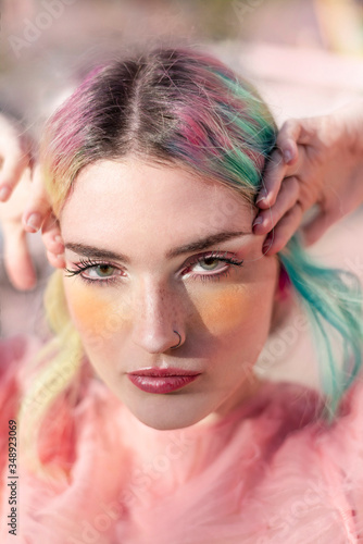 Fotografía Retrato de una mujer joven caucásica, de piel blanca con algunas pecas en la nariz, con el cabello turquesa y rosa
