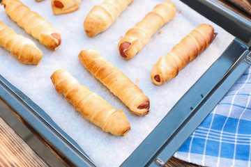 Sticker - Baked sausage rolls on the baking sheet on the wooden table. Hot dogs. Sausage in the dough.