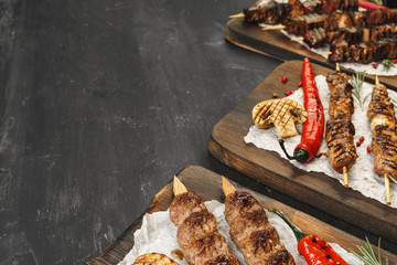 Wall Mural - Grilled Lula kebab on skewers served on wooden board, black table background