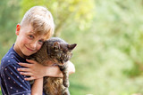 Fototapeta Na sufit - 
boy holding a cat in his arms