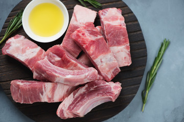 Wall Mural - Raw chopped pork ribs with seasonings on a black wooden cutting board, view from above, studio shot