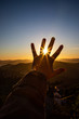 Leinwandbild Motiv Sunset sun rays view through the fingers of a feminine open hand