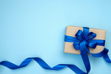 Gift Box With Blue Ribbon Bow Isolated On Blue Background. Present For Father's Day, Birthday Or International Men's Day Day. Festive Decor Background. Top View Flat Lay With Free Space. 