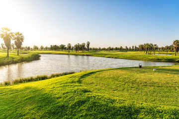 Wall Mural - Beautiful, with green grass, golf course, with a pond, with sunny blue and clear sky. Portugal, Algarve.