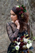 A beautiful woman in a black dress with a bouquet of flowers in a ghostly forest. Gothic beauty, mystical image
