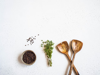 Wall Mural - Kitchen composition with wood spoons, black pepper and fresh thyme on a light background. Top view. Copy space