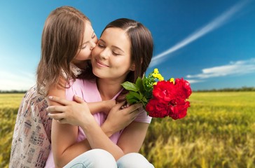 Wall Mural - Happy beautiful mother and daughter hugging with a bouquet