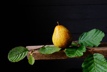 Ripe Yellow Pear And Green Leaves On Black Background
