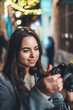 © A_B_C - Outdoor portrait photographer smile girl with retro camera take photo on background bokeh light in night city, Blogger photoshoot concept. Tourist  travels in Barcelona, photo hobby.
