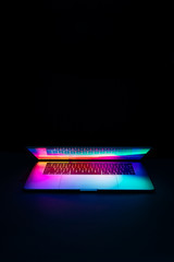 Isolated high tech open laptop with abstract vibrant color screen on a dark background.