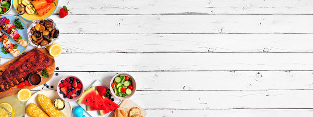 Summer BBQ or picnic food corner border. Assortment of grilled meat, vegetables, fruits, salad and potatoes. Overhead view over a white wood background. Copy space.