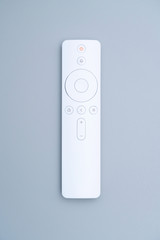 A white remote control placed on a blue-gray background.