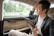 © komgritch - Young asian businessman using tablet and looking out of window while sitting on the back seat in the car. hurrying to work.