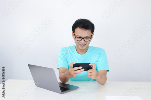 Fotografía Asian young man enjoy on the smartphone when play game at work