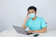 © Reezky - Young Asian man wearing medical mask is feeling unhealthy, tired, and confused with working in laptops on the table.