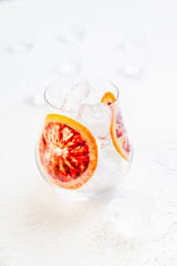 Wall Mural - A glass with ice cubes and two blood orange slices on white background