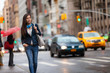 Young Asian professional woman walking home commuting from work in New York city street. Urban people lifestyle commuter in NYC traffic rain day. Chinese girl with purse and headphones for commute.