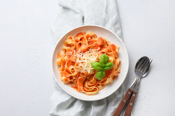 Fettuccine with tomato sauce with basil on white background. View from above.