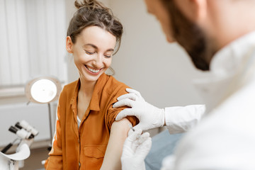 Healthcare worker gives an injection of a vaccine or some medication to a young girl in the office. Vaccination concept