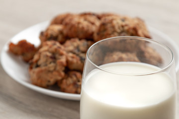 A glass of milk with cookies in the background