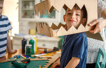 Smiling Boy Wearing A Cardboard Dinosaur Costume