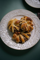 Wall Mural - Fresh pastries, hot tasty cinnamon rolls on a green background with a burgundy dishcloth. Buns for dessert for hot drinks. Top view.