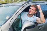 Angry aggressive guy, young emotional irritated man driver screaming, shouting, yelling while driving car, threatening with a fist from automobile window. Driving anger negative emotion, agression
