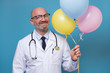 © Viktor Koldunov - Mature doctor in glasses with stethoscope holds several helium balloon celebrating his patient recovery