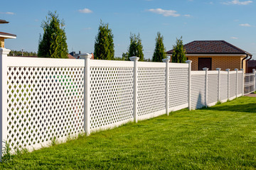 White vinyl fence in a cottage village. Several panels are connected by columns. Fencing of private property.