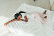 © LIGHTFIELD STUDIOS - high angle view of african american girl in pajamas sleeping on white bedding