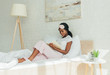 © LIGHTFIELD STUDIOS - attentive african american girl with sleep mask on forehead reading book while sitting in bed