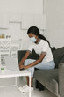 © LIGHTFIELD STUDIOS - young african american freelancer in medical mask working on laptop in kitchen