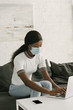 © LIGHTFIELD STUDIOS - young african american freelancer in medical mask working on laptop at home