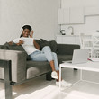 © LIGHTFIELD STUDIOS - happy african american freelancer in wireless headphones using digital tablet while sitting on sofa near table with laptop